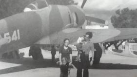 a woman and a man with two young children, standing in front of a plane
