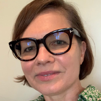 Kristen Hatch smiling and wearing black glasses. 