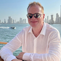Peter Krapp smiling with the ocean and a city skyline in the background. 