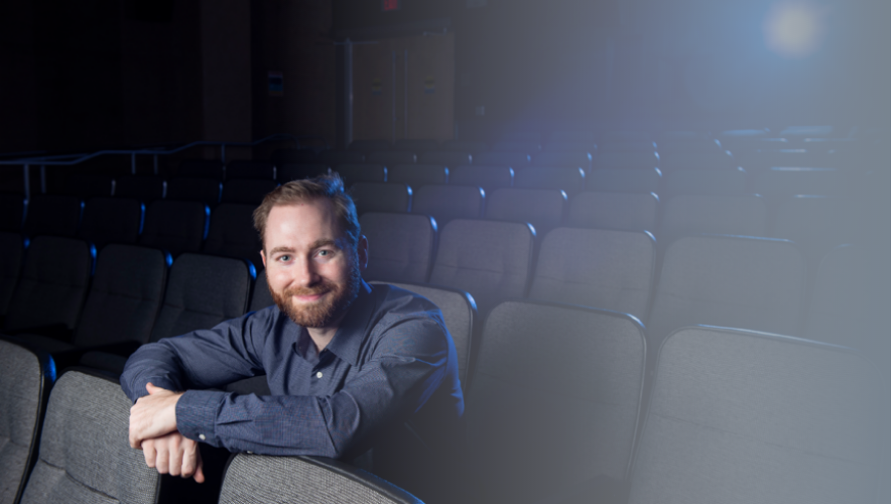 Finley Freibert leans against a chair in an empty theater