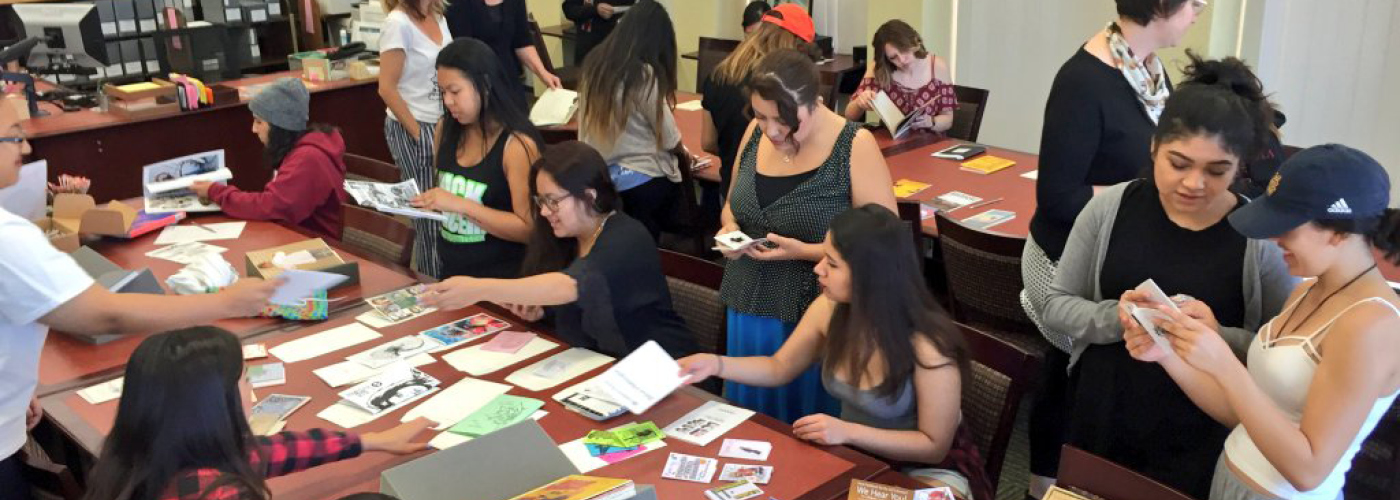 Students in Jeanne Scheper’s Feminist Cultural Studies course exploring zines and an artist's book in UCI's Special Collections and Archives.