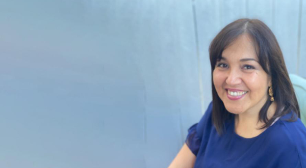 A headshot of Lauren Gómez against a pale gray background