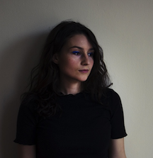 a moody portrait of a young woman against a wall