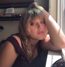 a femme-presenting young person leans on a windowsill 