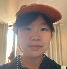 a person with an orange hat smiles slightly at the camera in a selfie pose