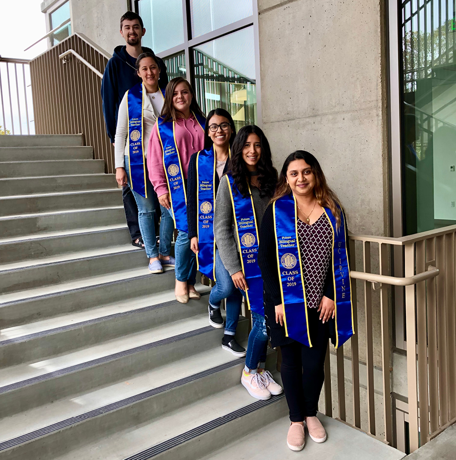Students wearing graduation stoles are lined up on a set of stairs