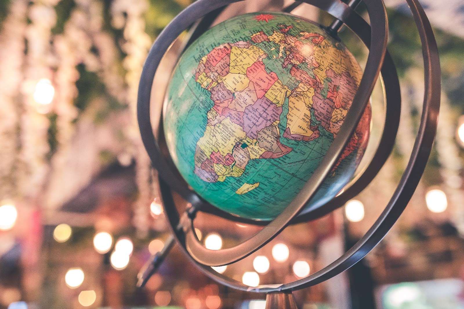 A globe tilted with light and flowers, blurred in the background