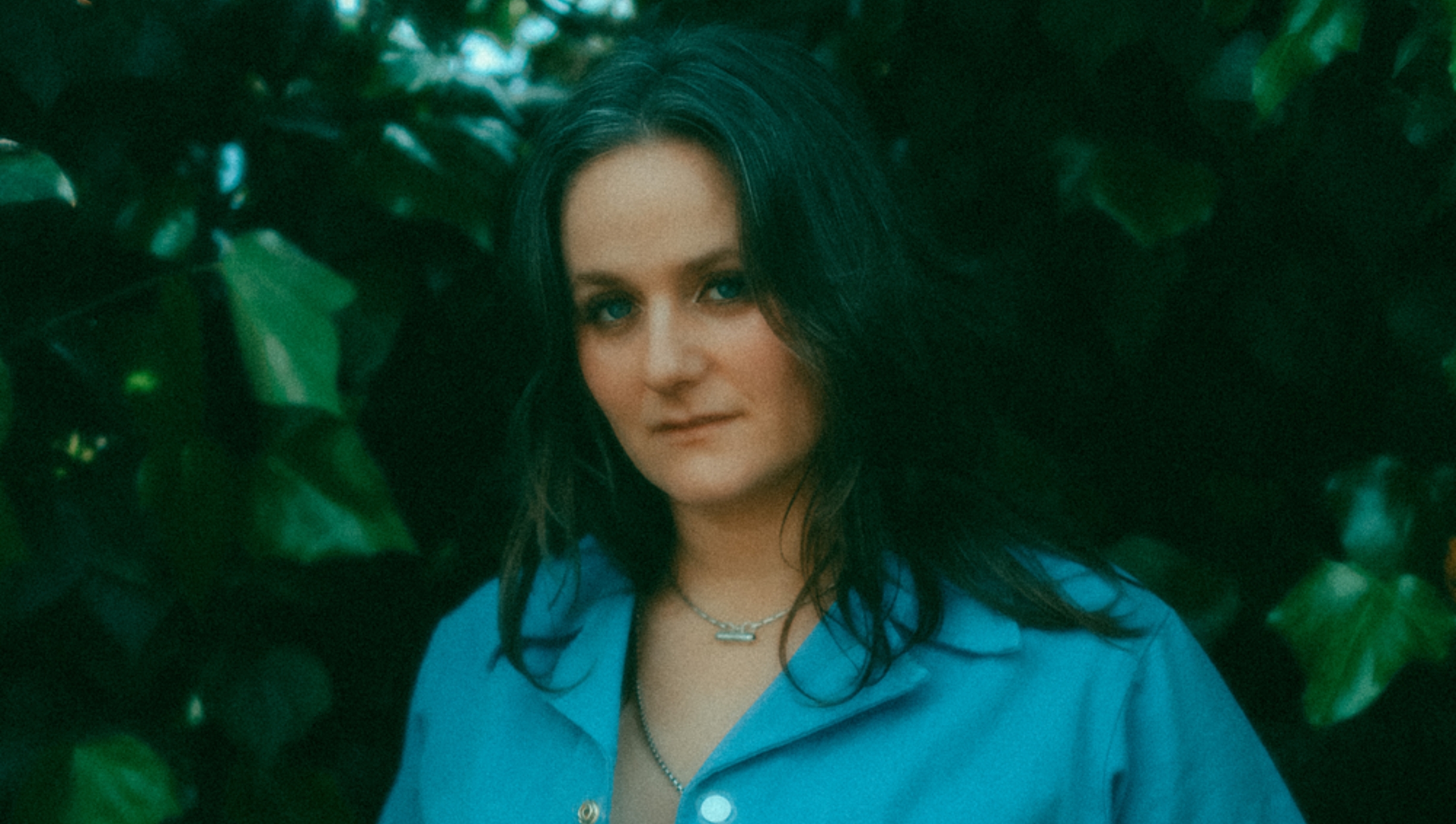 Headshot of Bee Sacks against a greenery background