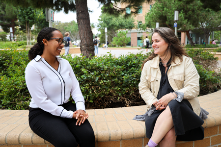 Ashley Bell and Bee Sacks sitting on campus