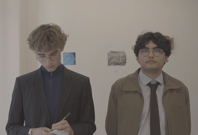 Two men stand in an art gallery. 