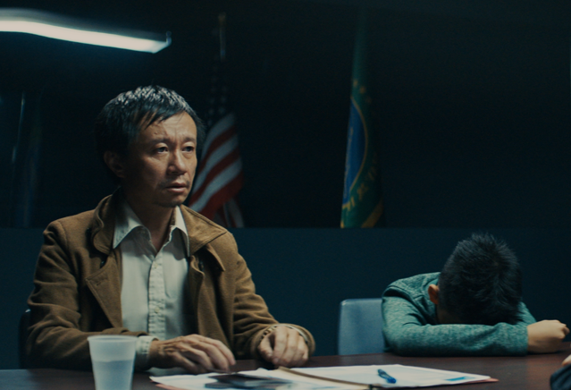 A father and sun sit in an immigration office. 