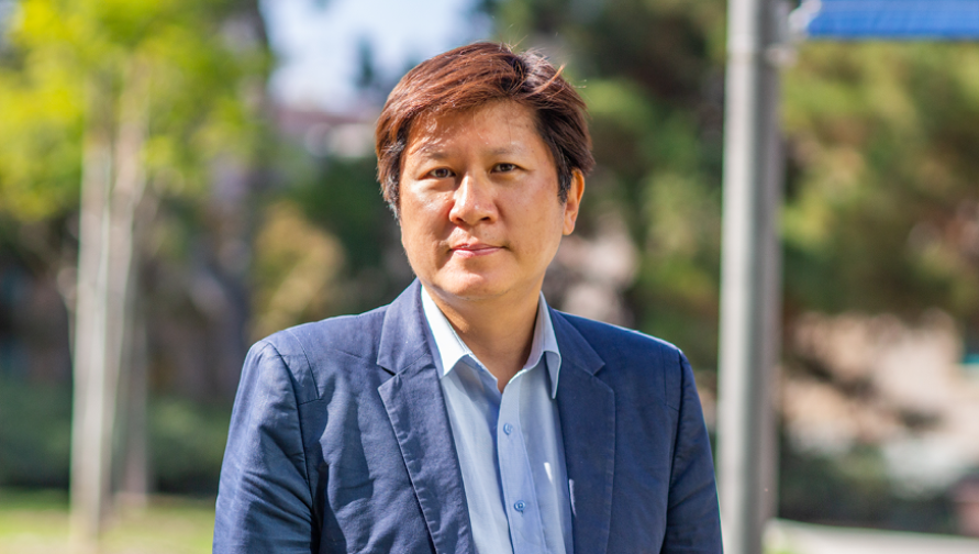 Professor Kyung Hyun Kim wearing a blue suit and standing outdoors