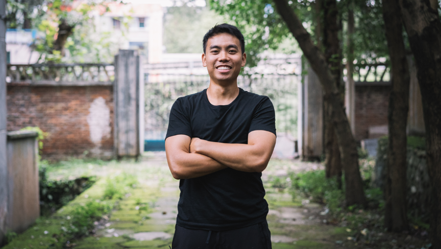 Sheldon Chau standing in a garden with his arms folded