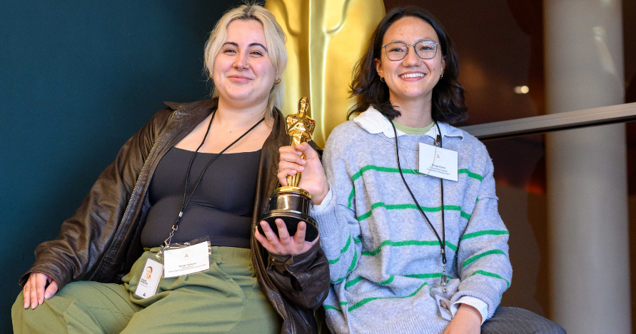 Olivia Clark sitting on a statue of an Emmy award
