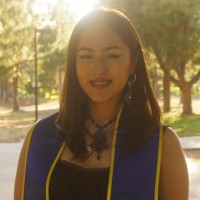 Head and shoulders of young woman with dark shoulder-length hair wearing UCI graduation stole