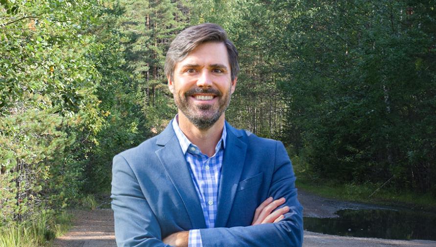 James Nisbet stands before a forest thick with trees