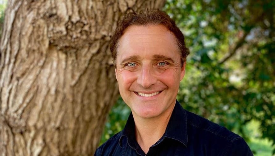 A headshot of John Gamber in front of a tree