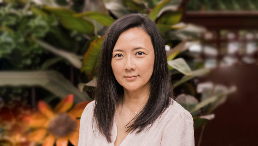 A headshot of Julia Lee against a background of foliage