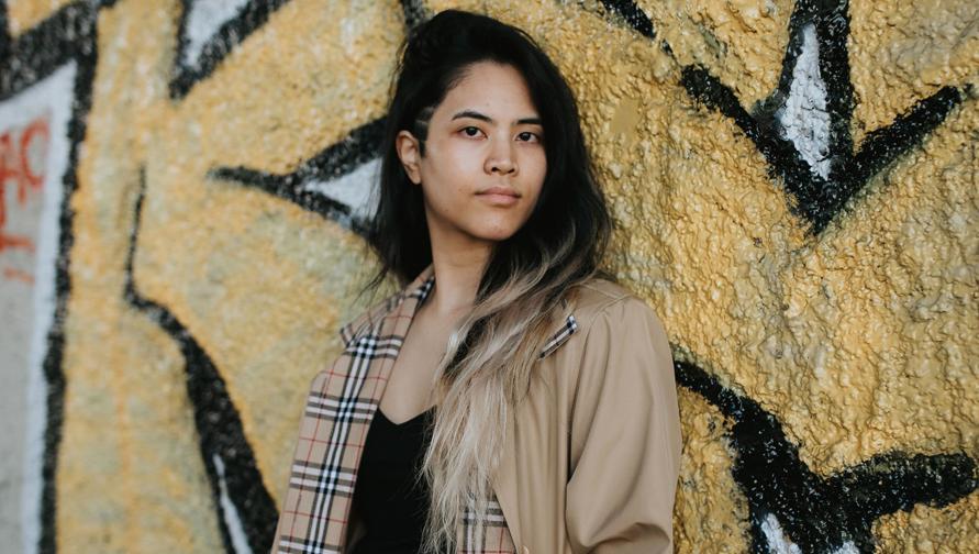 Nicole Dizon posing in front of graffiti. 