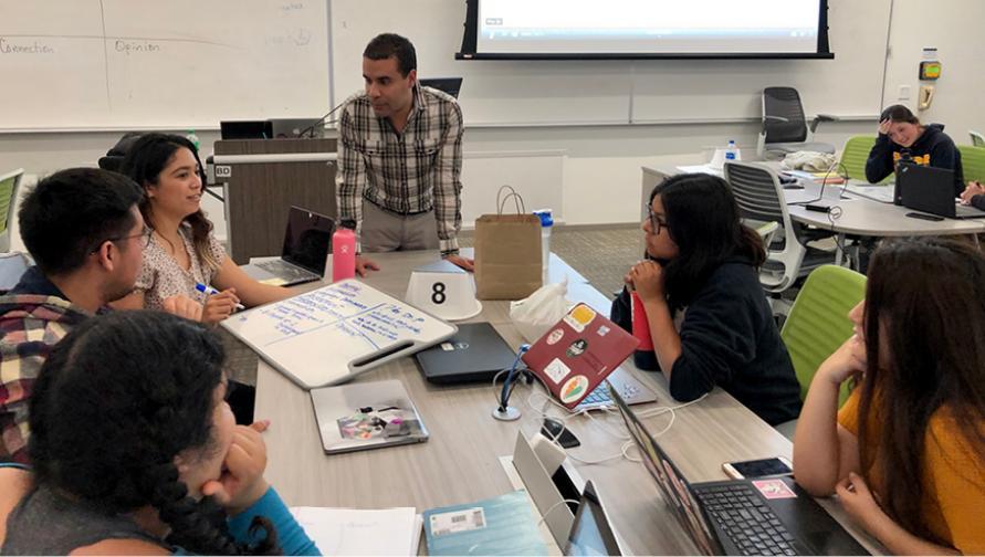 Spanish Professor Julio Torres instructs a group of students sitting at a table