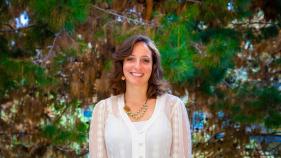 Rena Goldstein is smiling in front of pine trees