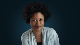 Faculty member Bridget Cooks poses in front of a dark blue background