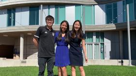 Three literary journalism students pose for a photo in front of Humanities Gateway