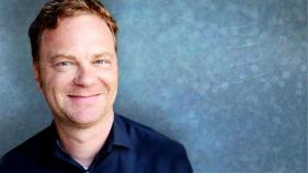 A headshot of Peter Krapp against a bluish gray background