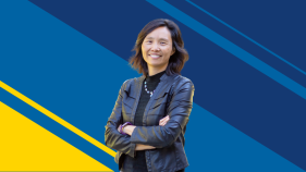 Asian American woman smiling with arms crossed standing against UCI blue and gold background