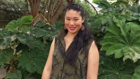 Larissa Fong standing in front of a bunch of greenery.