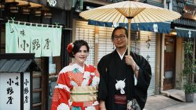 woman wearing red kimono next to man wearing black kimono on street in Japan