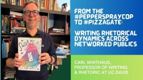 Carl Whithaus holding their book titled Swarms, Viral Writing, and the Local: Rhetorical Dynamics across Networked Publics