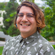 Close up of E.M. Hernandez smiling with bushes in the background