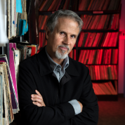 Jim Guerinot crossing his arms and leaning against a book case