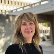 Kelly Brown smiling with UCI buildings behind her