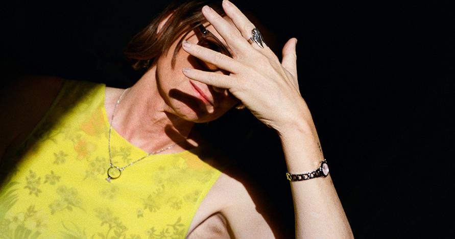 woman against black background with hand covering her face
