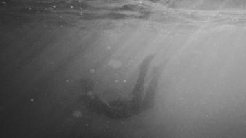 black and white photo of body floating under water