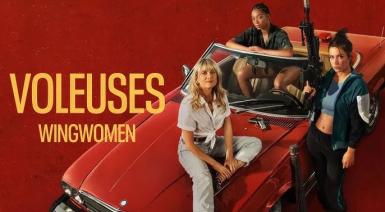 Three women smirking eith one holding a weapon
