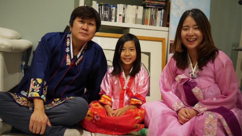 Kyung Hyun Kim sits with his daughter, Sidd Kim, and wife, Yourim Lee, wearing hanbok for the Lunar New Year