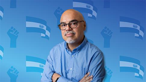 Hector Tobar in the foreground, behind images of an El Salvador flag