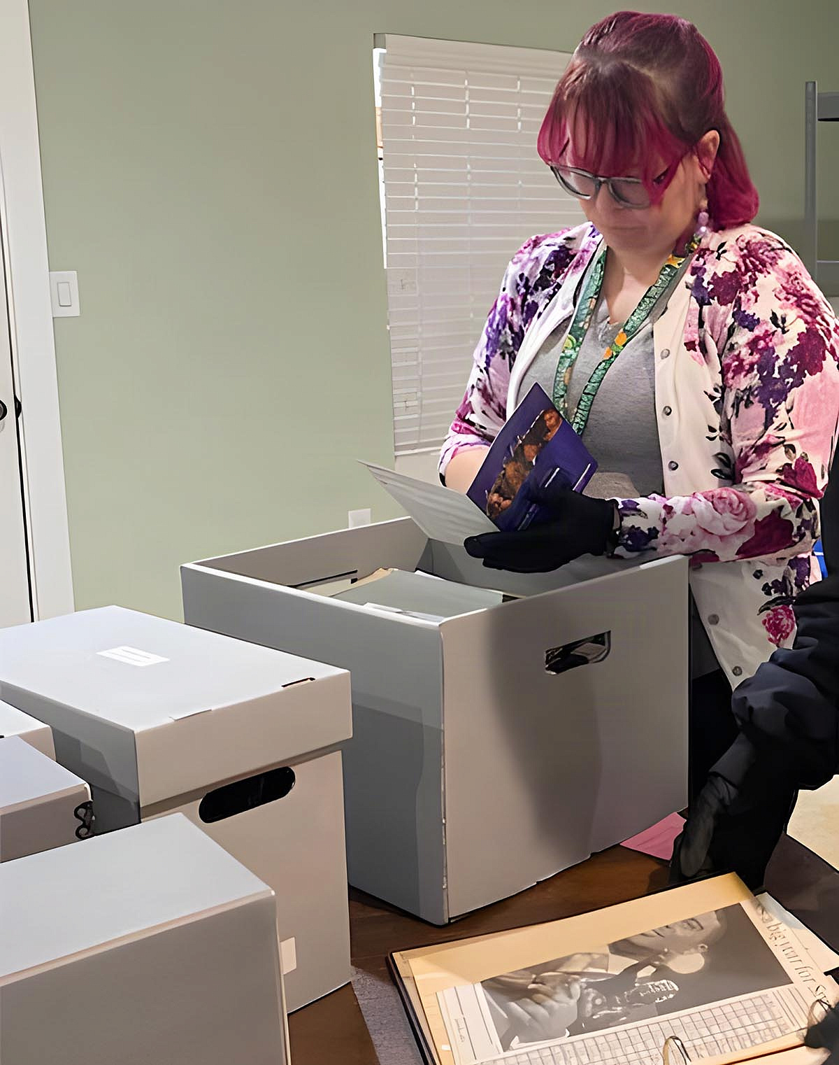 Elizabeth Lieb examines a printed piece in front of archival boxes.