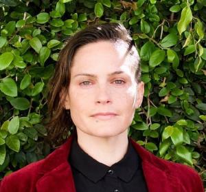 Headshot of woman with brown hair wearing black shirt and red jacket