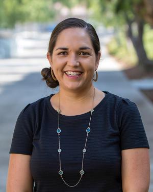 Smiling woman wearing blue short-sleeved sweater and long necklace