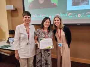 Adria Imada standing between two women holding her award