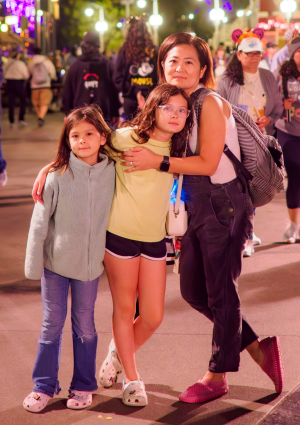 A woman posing with two young girls at Disneyland
