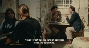 Two men sitting at a table with the text "Never forget this is a land of conflicts since the beginning."