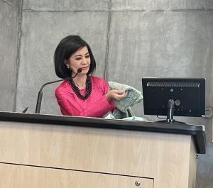 Frances Nguyen behind a podium holding clothing