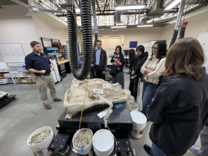 The group standing in a circle, listening to the staff member talk about bones.