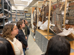 Students looking at old wooden and straw masks and drums in Bowers Collections Storage.