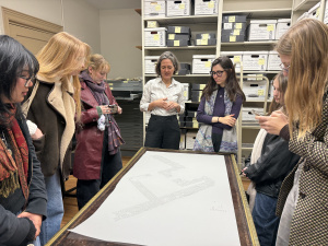 Professor Acosta and students looking at a large paper as the curator talks.